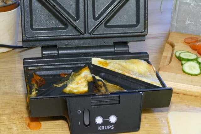Sandwichmaker nach der Zuberereiung von Pizza Sandwiches
